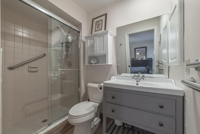 bathroom with hardwood / wood-style flooring, a shower with shower door, vanity, and toilet