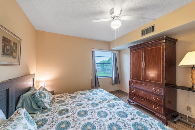 bedroom featuring ceiling fan, dark hardwood / wood-style floors, and a textured ceiling