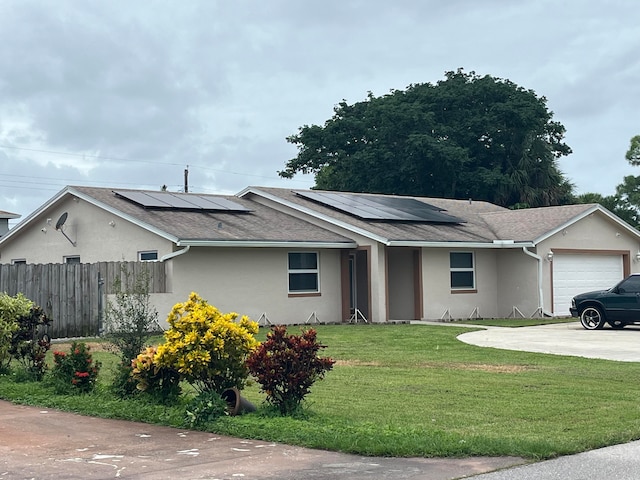 ranch-style home featuring solar panels, a front yard, and a garage