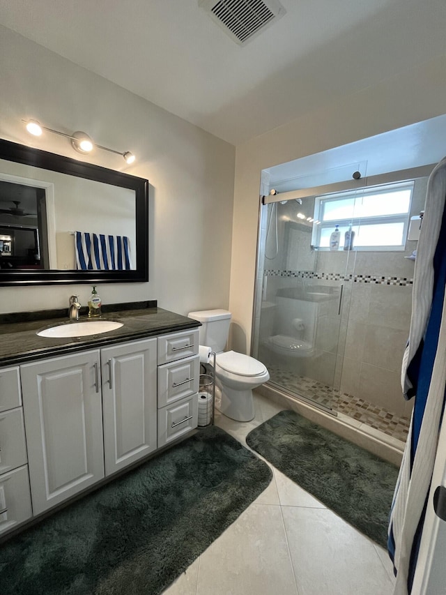 bathroom featuring tile patterned flooring, a shower with shower door, vanity, and toilet