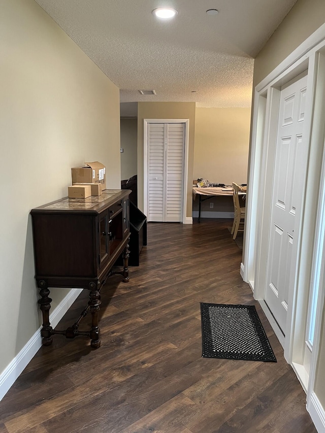 hallway featuring dark hardwood / wood-style floors and a textured ceiling