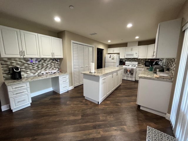 kitchen with built in desk, white cabinetry, white appliances, and a kitchen island