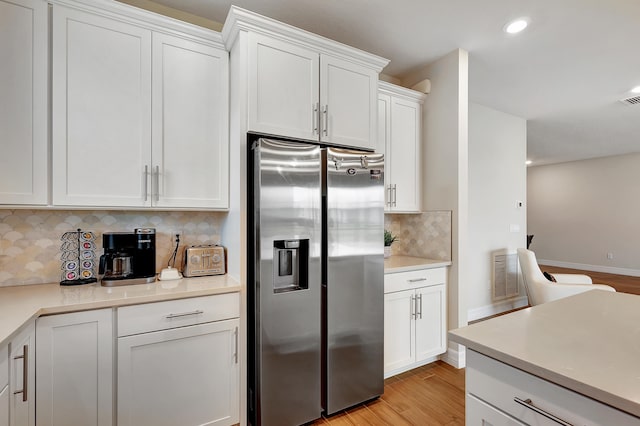 kitchen with white cabinets, light hardwood / wood-style flooring, tasteful backsplash, and stainless steel fridge with ice dispenser