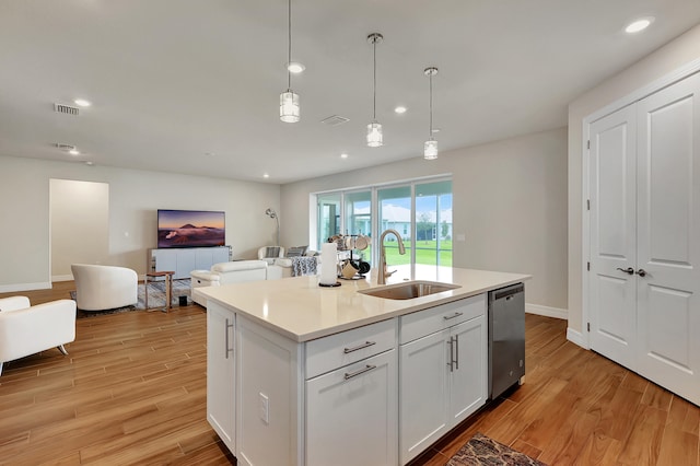 kitchen with stainless steel dishwasher, white cabinets, sink, light hardwood / wood-style flooring, and decorative light fixtures