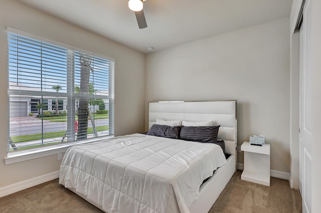 carpeted bedroom featuring ceiling fan and a closet