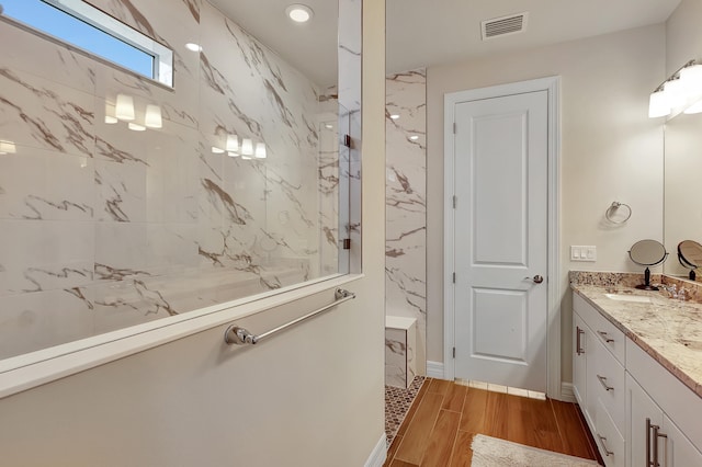 bathroom with a tile shower, vanity, and hardwood / wood-style floors