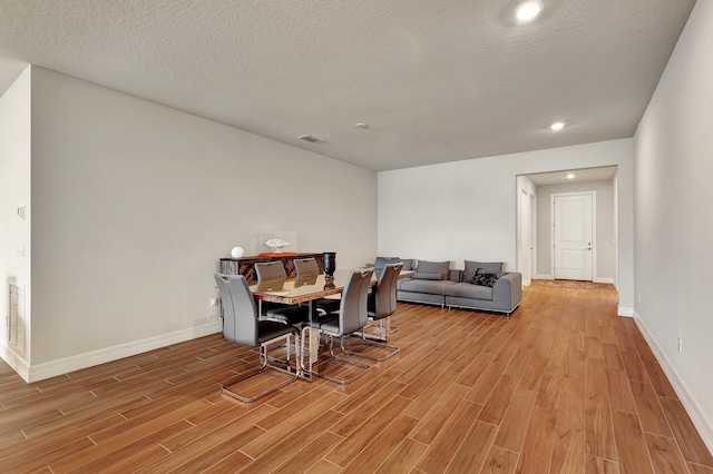 dining room with a textured ceiling and light hardwood / wood-style floors