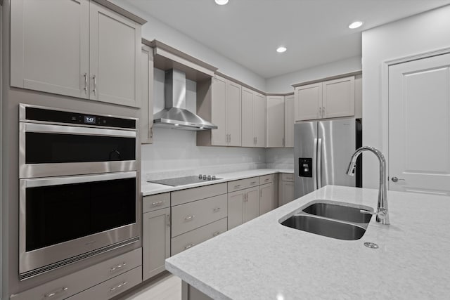 kitchen with wall chimney exhaust hood, gray cabinets, stainless steel appliances, and sink