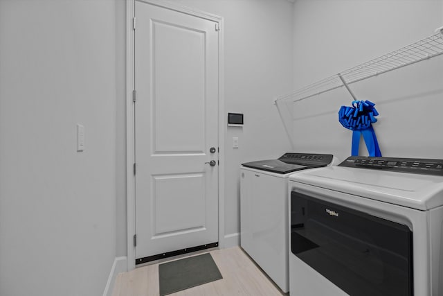 clothes washing area with light wood-type flooring and washer and clothes dryer