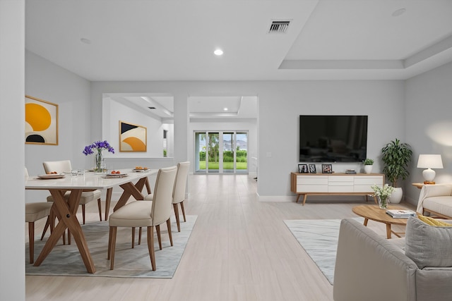 living room featuring light wood-type flooring and a raised ceiling