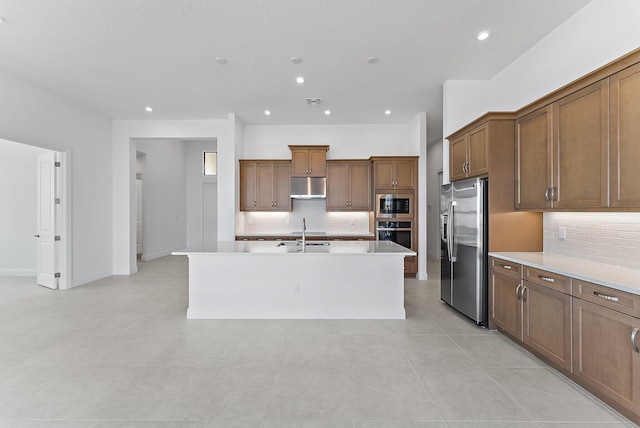 kitchen featuring tasteful backsplash, sink, a center island with sink, and appliances with stainless steel finishes