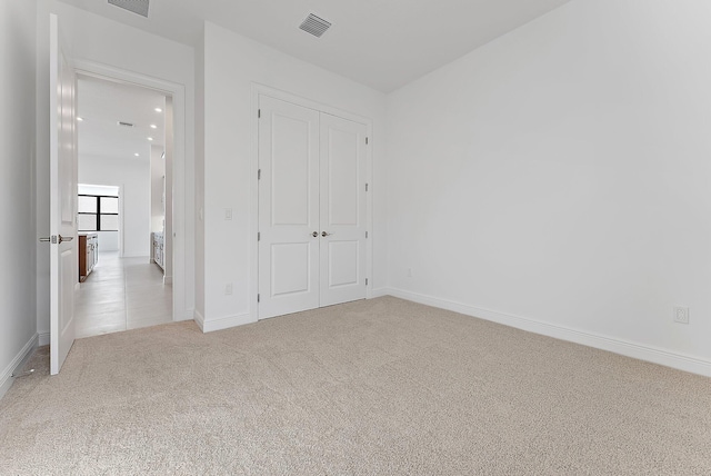 unfurnished bedroom with light colored carpet and a closet