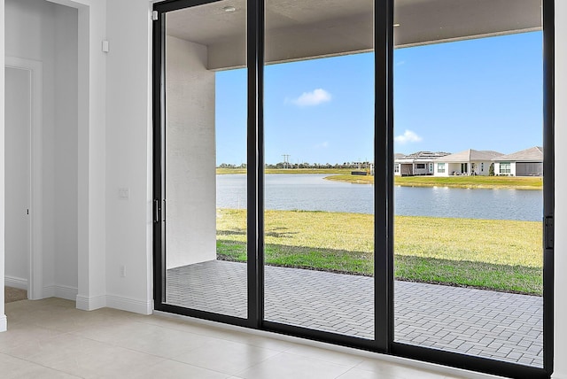 doorway with light tile patterned floors and a water view