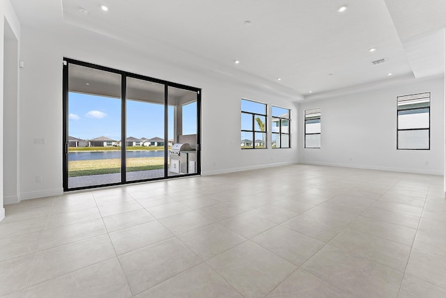 spare room with a raised ceiling and light tile patterned flooring