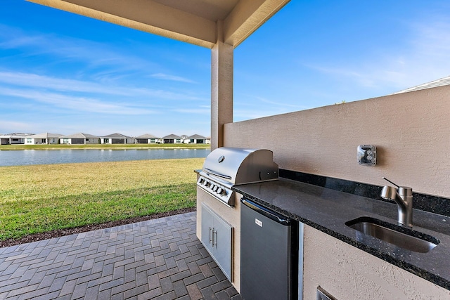 view of patio / terrace with sink, grilling area, a water view, and exterior kitchen