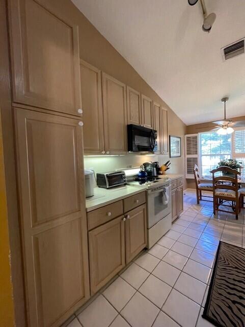 kitchen with light brown cabinets, lofted ceiling, ceiling fan, light tile patterned floors, and white range oven