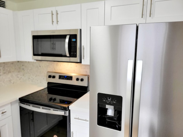 kitchen featuring appliances with stainless steel finishes, decorative backsplash, and white cabinetry