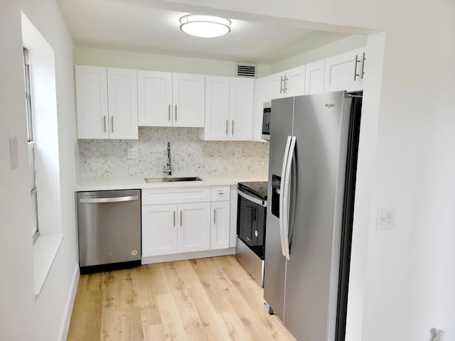 kitchen with appliances with stainless steel finishes, sink, light hardwood / wood-style floors, and white cabinets