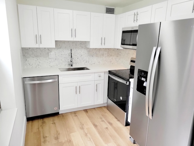 kitchen featuring stainless steel appliances, light hardwood / wood-style floors, sink, and white cabinetry