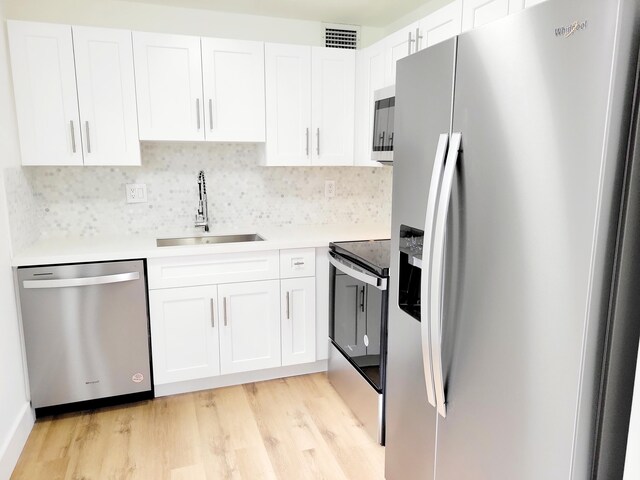 15 Burgundy Unit A, Delray Beach, FL 33484 - kitchen featuring light wood finished floors, stainless steel appliances, white cabinets, and a sink