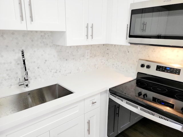 15 Burgundy Unit A, Delray Beach, FL 33484 - kitchen featuring stainless steel appliances, a sink, white cabinetry, decorative backsplash, and light countertops