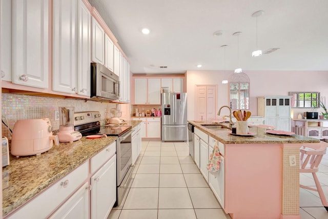 kitchen with white cabinets, an island with sink, hanging light fixtures, sink, and appliances with stainless steel finishes