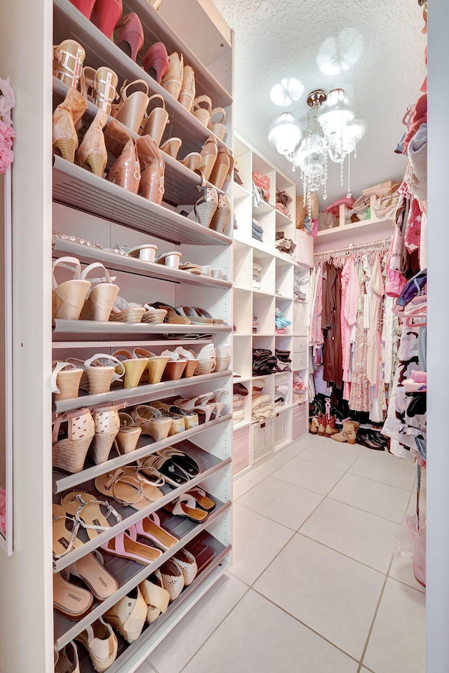 walk in closet with a notable chandelier and tile patterned flooring