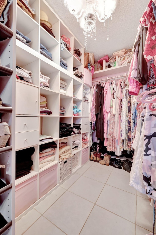 walk in closet featuring a chandelier and light tile patterned floors