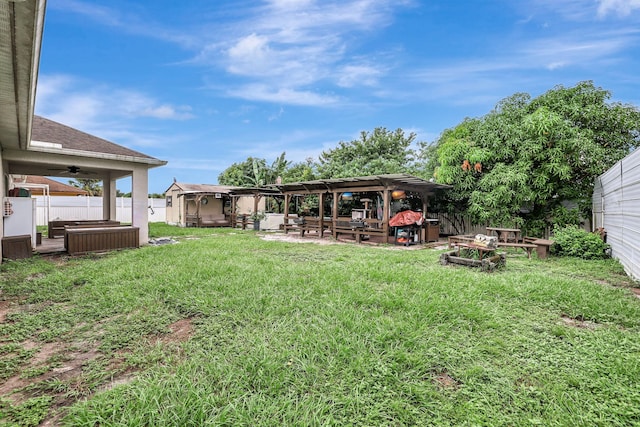 view of yard with ceiling fan, a patio area, a hot tub, and an outdoor fire pit