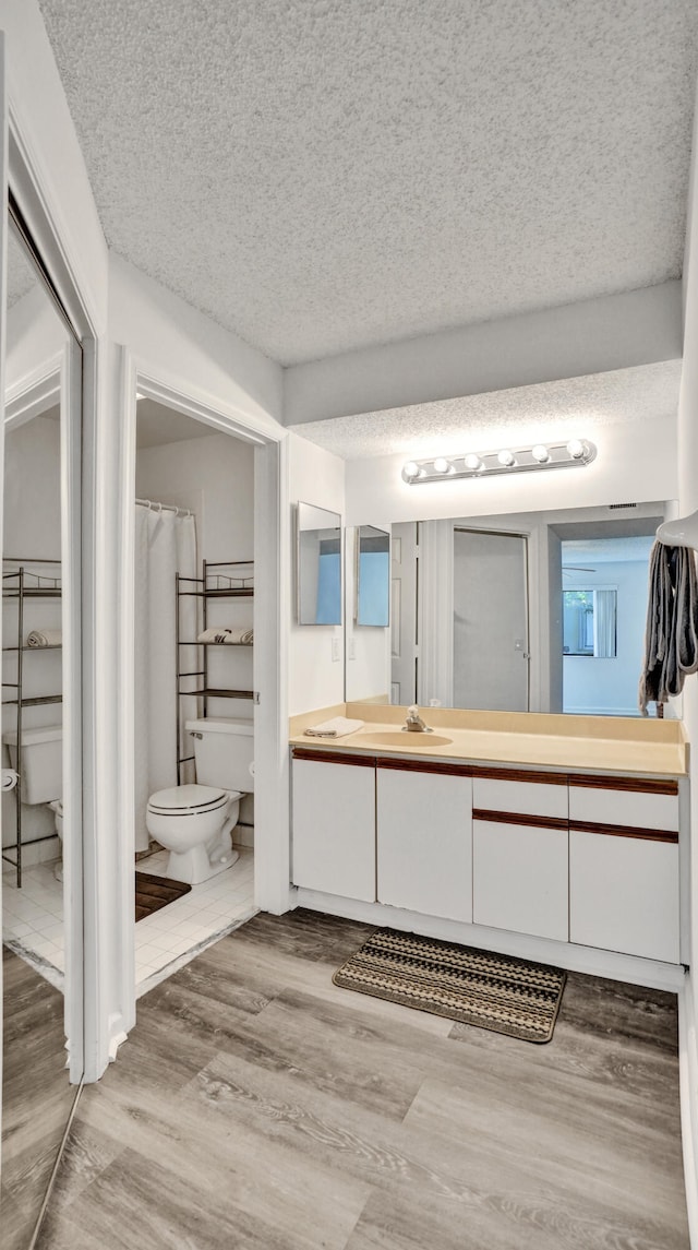 bathroom with hardwood / wood-style floors, vanity, toilet, and a textured ceiling