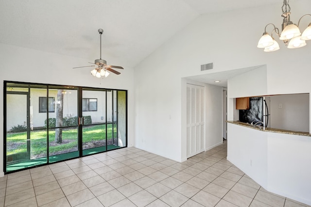 tiled empty room with ceiling fan with notable chandelier and high vaulted ceiling