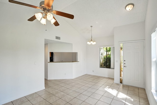 tiled spare room featuring ceiling fan with notable chandelier, high vaulted ceiling, and a textured ceiling