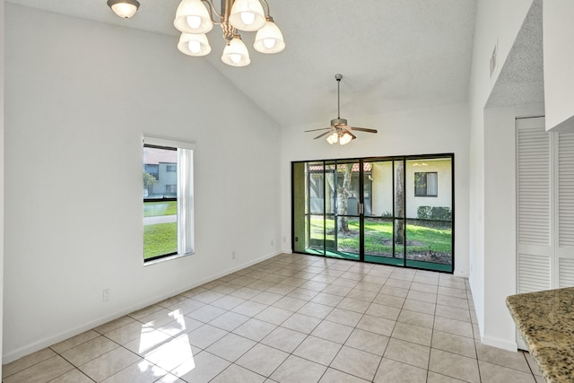 empty room with a textured ceiling, ceiling fan with notable chandelier, light tile patterned floors, and high vaulted ceiling