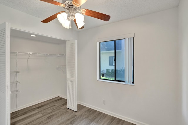 unfurnished bedroom featuring ceiling fan, a closet, hardwood / wood-style floors, and a textured ceiling