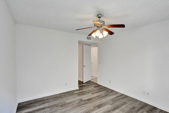 empty room with ceiling fan, dark hardwood / wood-style flooring, and a textured ceiling