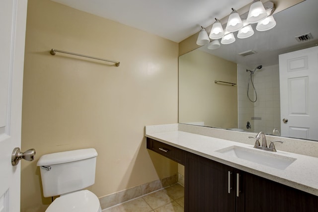 bathroom featuring tile patterned flooring, vanity, tiled shower, and toilet