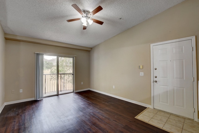 empty room with lofted ceiling, wood-type flooring, ceiling fan, and a textured ceiling