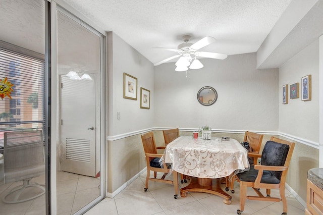 dining area with ceiling fan, light tile patterned floors, and a textured ceiling