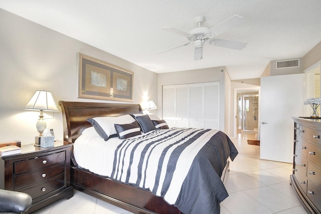 bedroom with light tile patterned flooring, ceiling fan, a closet, and a textured ceiling