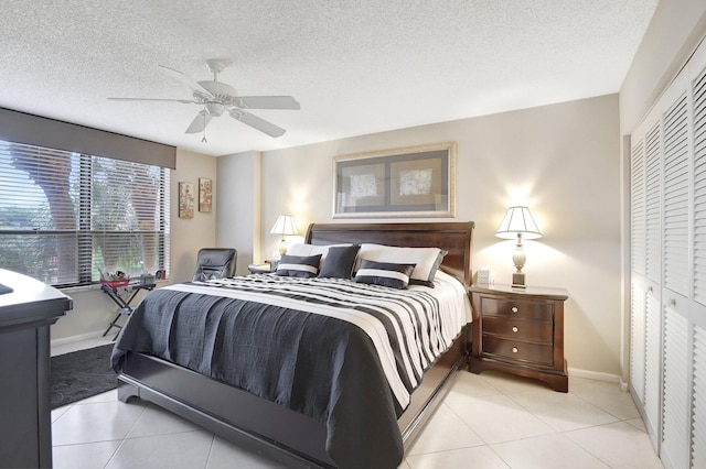 tiled bedroom with ceiling fan, a closet, and a textured ceiling