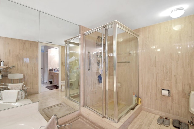 bathroom featuring wood walls, a shower with door, and toilet