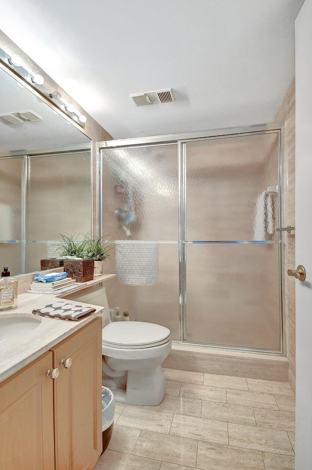 bathroom featuring vanity, a shower with shower door, and toilet