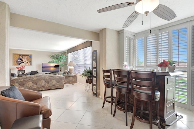 interior space featuring ornamental molding, ceiling fan, light tile patterned flooring, and a textured ceiling