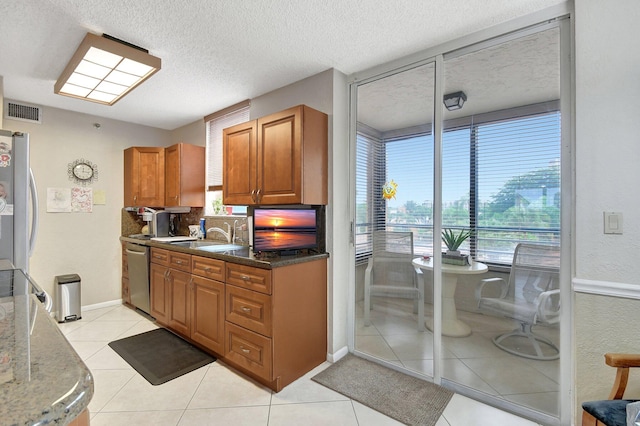 kitchen with tasteful backsplash, dark stone counters, appliances with stainless steel finishes, light tile patterned floors, and a textured ceiling