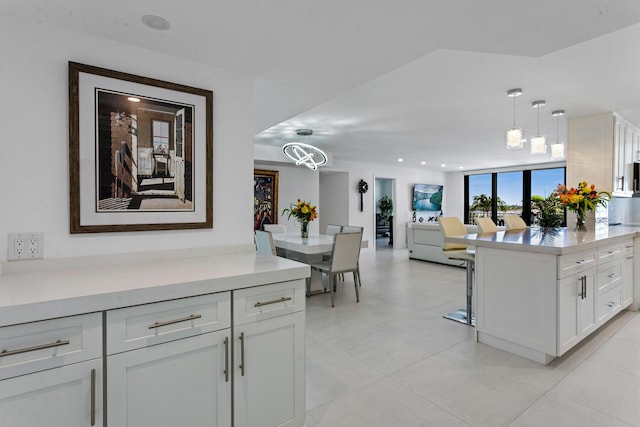 kitchen with white cabinets, pendant lighting, light tile patterned floors, and a notable chandelier