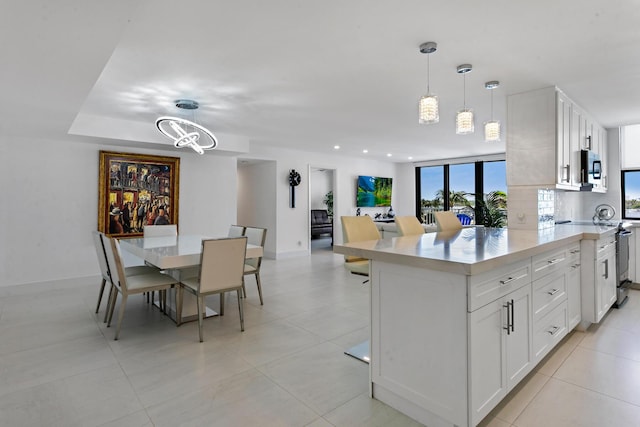 kitchen with appliances with stainless steel finishes, tasteful backsplash, an inviting chandelier, white cabinets, and hanging light fixtures