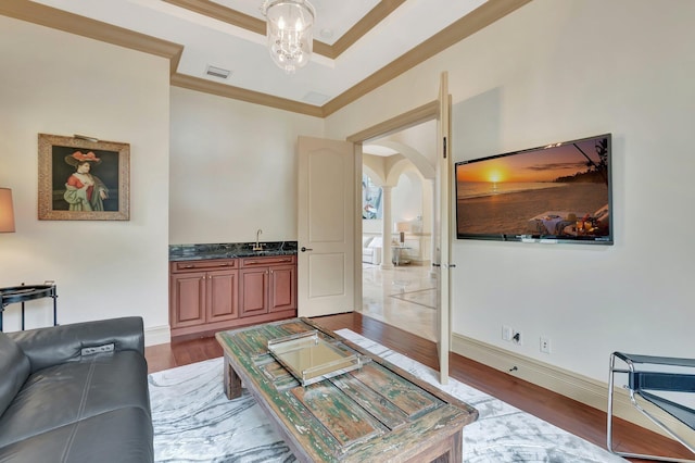 living room featuring sink, a raised ceiling, crown molding, and light hardwood / wood-style flooring