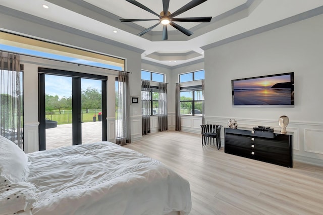 bedroom with multiple windows, access to exterior, ceiling fan, and a tray ceiling