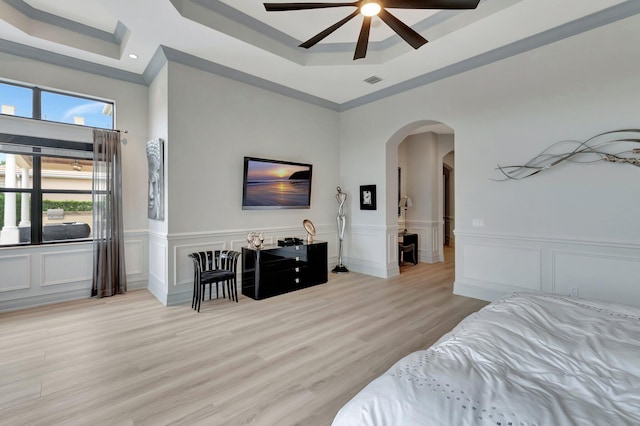 bedroom featuring ceiling fan, light wood-type flooring, and a raised ceiling