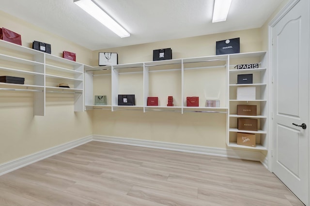 walk in closet with light hardwood / wood-style flooring